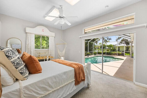 carpeted bedroom featuring multiple windows, ceiling fan, and access to exterior