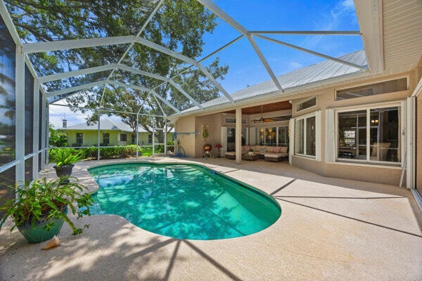 view of pool featuring a patio, glass enclosure, and ceiling fan