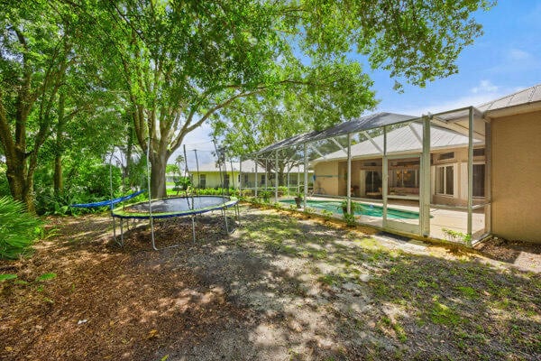 view of yard featuring glass enclosure and a trampoline