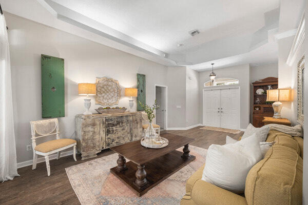 living room with a tray ceiling and dark hardwood / wood-style floors