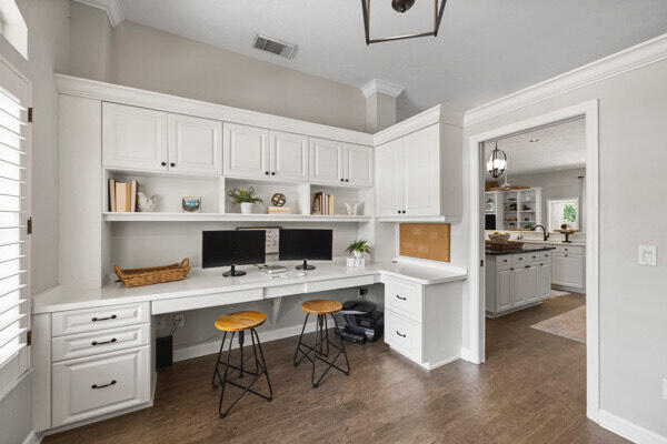 office space with built in desk, ornamental molding, and dark hardwood / wood-style floors