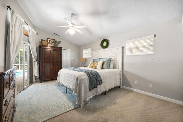 carpeted bedroom featuring a closet, lofted ceiling, and ceiling fan