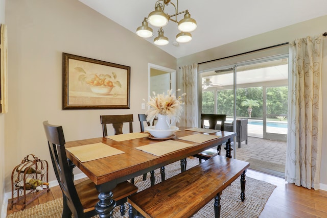 dining space with wood-type flooring, a notable chandelier, and lofted ceiling