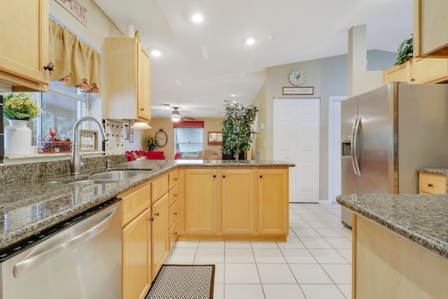 kitchen featuring appliances with stainless steel finishes, kitchen peninsula, lofted ceiling, light brown cabinetry, and sink