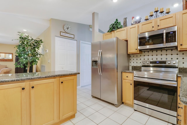 kitchen with dark stone counters, decorative backsplash, stainless steel appliances, light brown cabinets, and light tile patterned floors