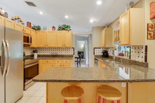 kitchen featuring sink, kitchen peninsula, a kitchen breakfast bar, stainless steel appliances, and light brown cabinets