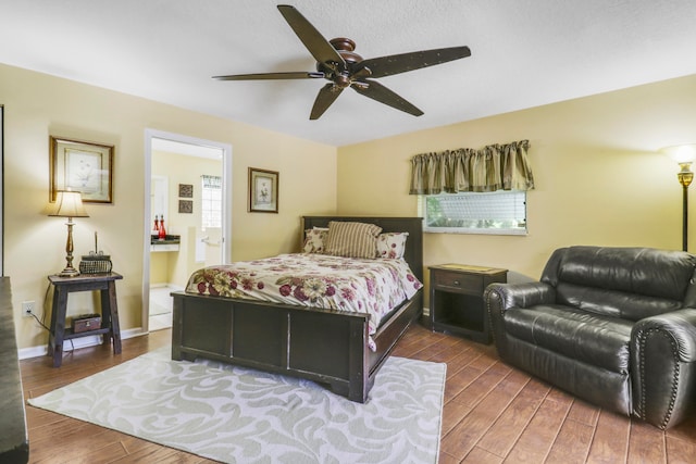 bedroom featuring ceiling fan, connected bathroom, dark wood-type flooring, and multiple windows