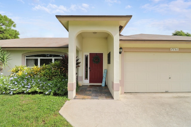 view of exterior entry featuring a lawn and a garage