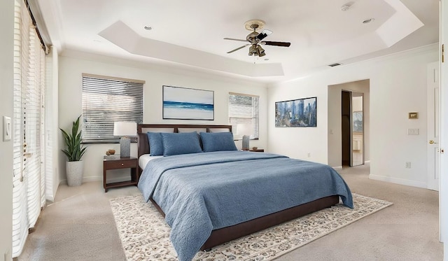 bedroom with light carpet, ceiling fan, and a raised ceiling