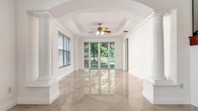 spare room featuring a tray ceiling, ornate columns, and ceiling fan