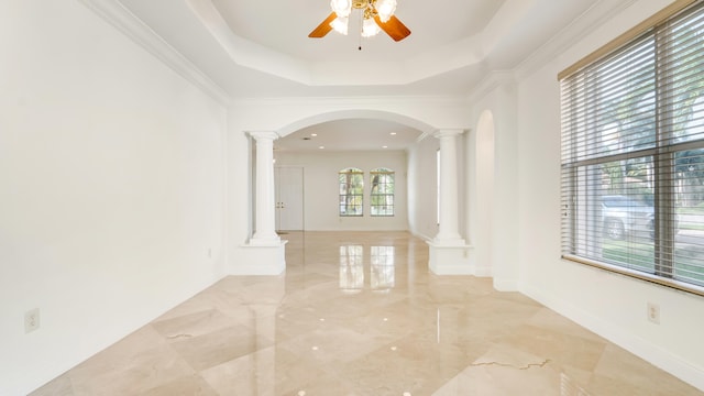 hall with ornate columns, ornamental molding, and a tray ceiling