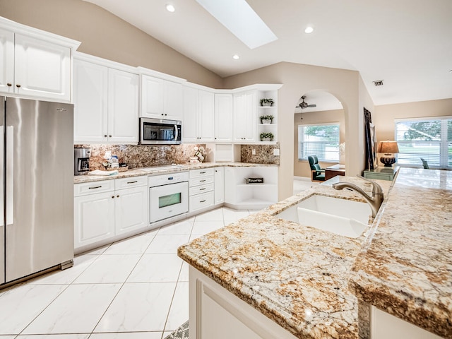 kitchen featuring white cabinetry, lofted ceiling with skylight, appliances with stainless steel finishes, and sink