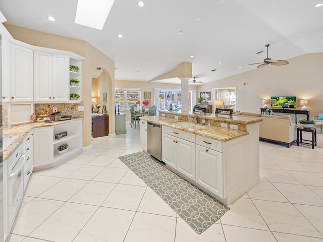 kitchen featuring light stone countertops, lofted ceiling, stainless steel dishwasher, and white cabinets