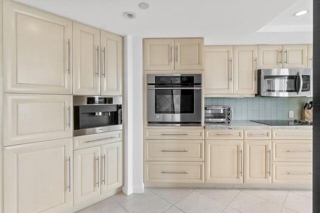 kitchen with light stone counters, stainless steel appliances, decorative backsplash, and light tile patterned flooring