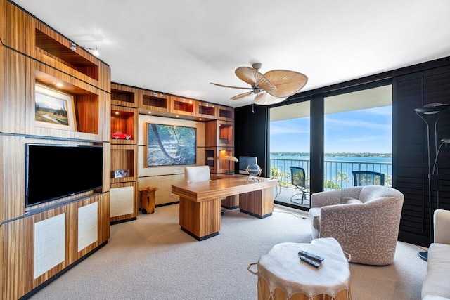 home office with built in shelves, wooden walls, light colored carpet, and ceiling fan