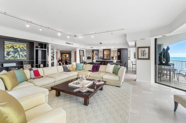 living room featuring crown molding, a water view, and rail lighting