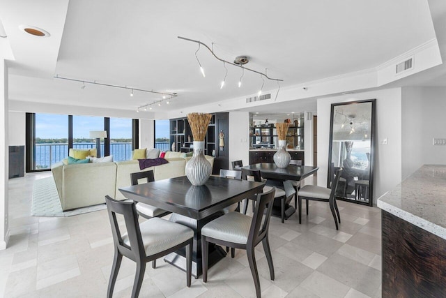 dining area with track lighting and a water view