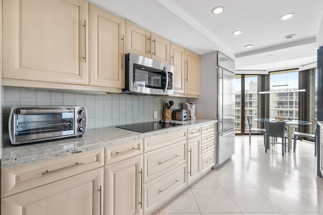 kitchen with light stone counters, stainless steel appliances, tasteful backsplash, and light tile patterned floors