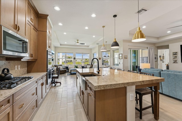 kitchen featuring a large island, a kitchen bar, appliances with stainless steel finishes, decorative light fixtures, and ceiling fan