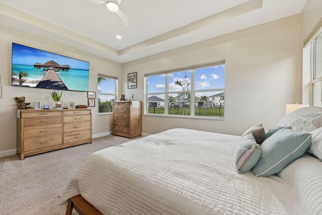 carpeted bedroom featuring a raised ceiling and ceiling fan