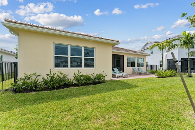 back of property featuring a lawn and a patio