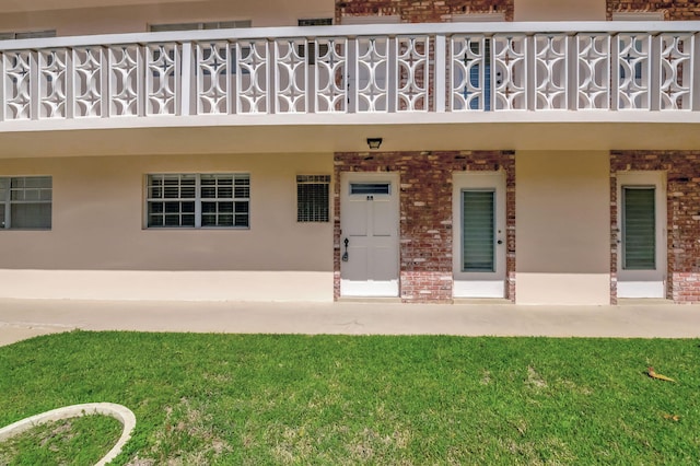 entrance to property with a yard and a balcony