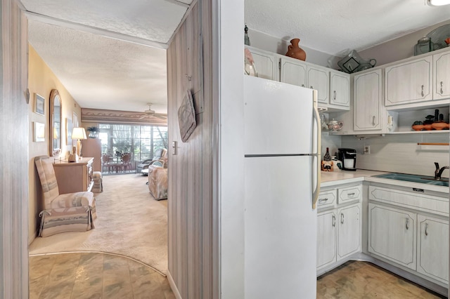 kitchen with light carpet, sink, white refrigerator, white cabinetry, and a textured ceiling