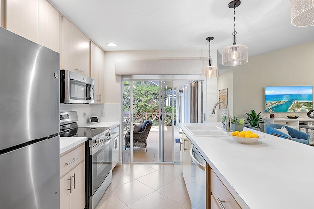 kitchen with stainless steel appliances, sink, light brown cabinets, light tile patterned floors, and decorative light fixtures