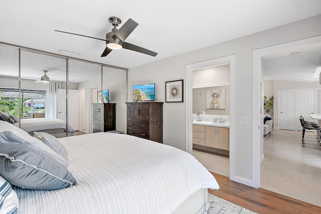 bedroom featuring ensuite bath, ceiling fan, light hardwood / wood-style flooring, and sink