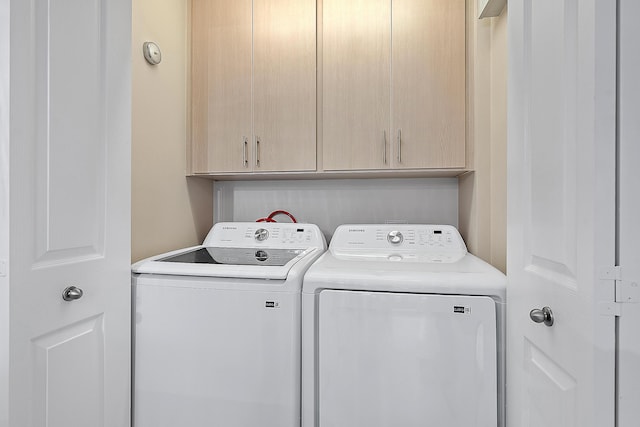 laundry area featuring separate washer and dryer and cabinets