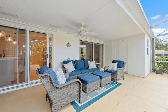 view of patio with outdoor lounge area, glass enclosure, ceiling fan, and sink