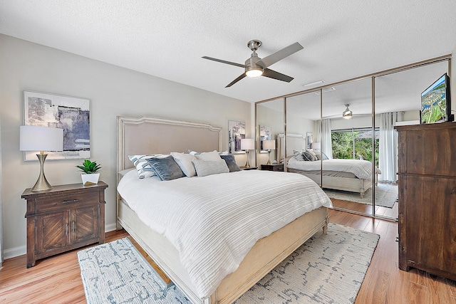 bedroom featuring ceiling fan, light wood-type flooring, a textured ceiling, and a closet