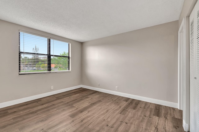 empty room with a textured ceiling and wood-type flooring