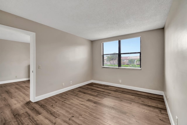 unfurnished room featuring dark wood-type flooring and a textured ceiling