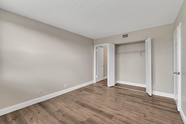 unfurnished bedroom with a closet, a textured ceiling, and hardwood / wood-style floors