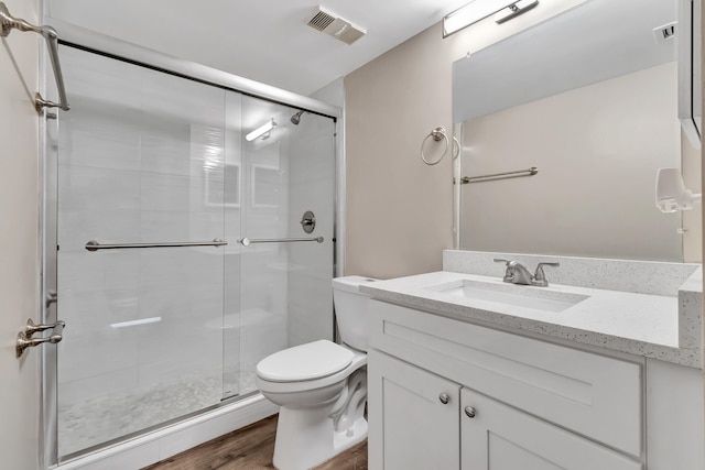 bathroom with vanity, toilet, wood-type flooring, and an enclosed shower