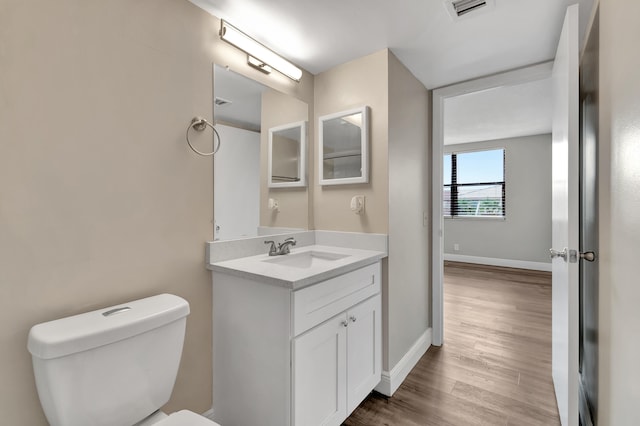 bathroom with toilet, vanity, and wood-type flooring