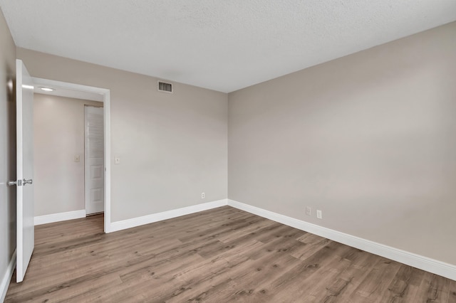 unfurnished room featuring a textured ceiling and light hardwood / wood-style flooring