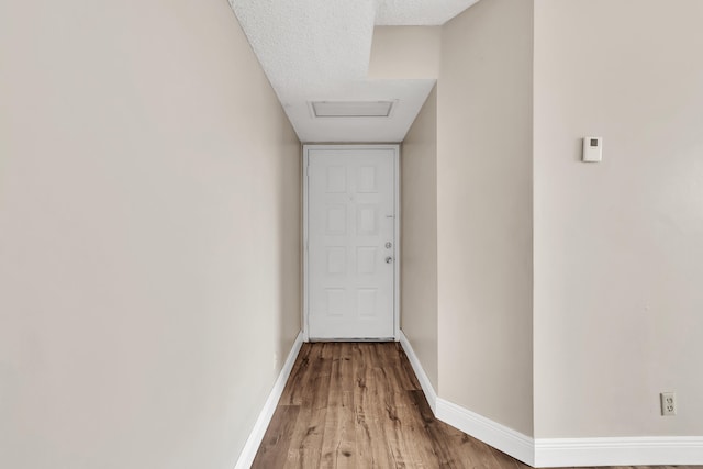 hallway with a textured ceiling and light wood-type flooring