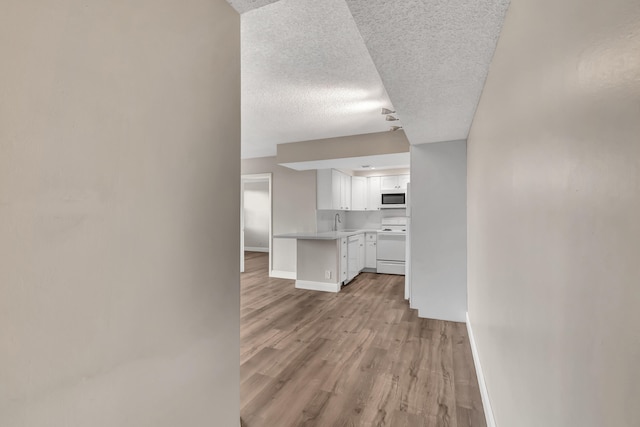 hall with light hardwood / wood-style floors, a textured ceiling, and sink