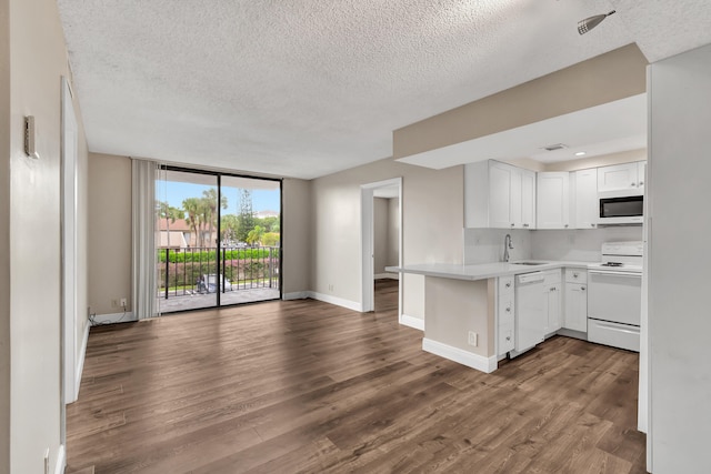 kitchen with kitchen peninsula, white cabinetry, a textured ceiling, wood-type flooring, and white appliances