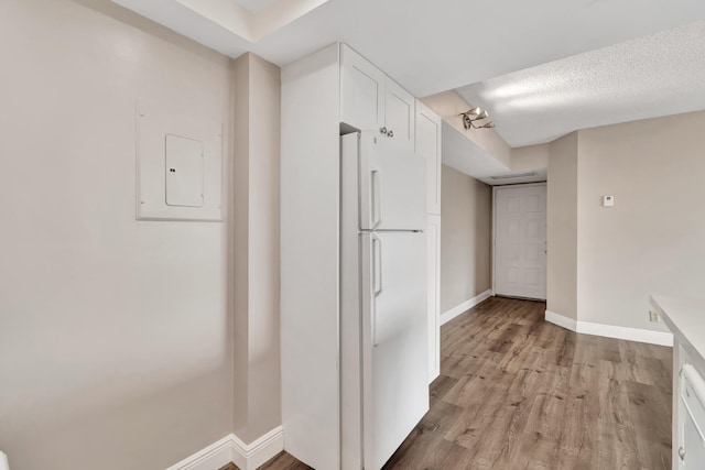 hallway with electric panel, light hardwood / wood-style flooring, and a textured ceiling