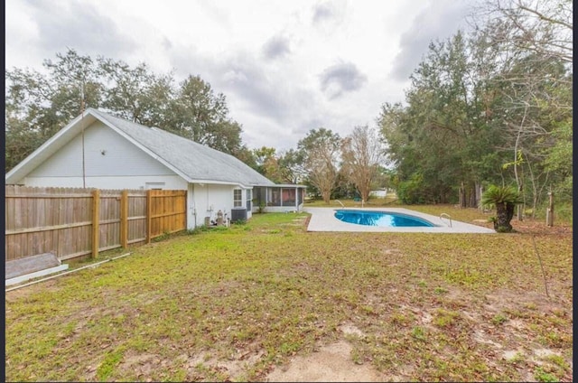 view of yard featuring a sunroom and a fenced in pool