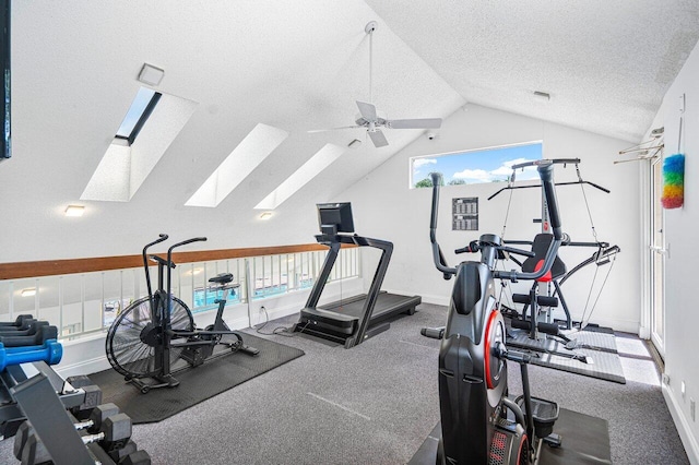 exercise area with ceiling fan, a textured ceiling, and lofted ceiling with skylight