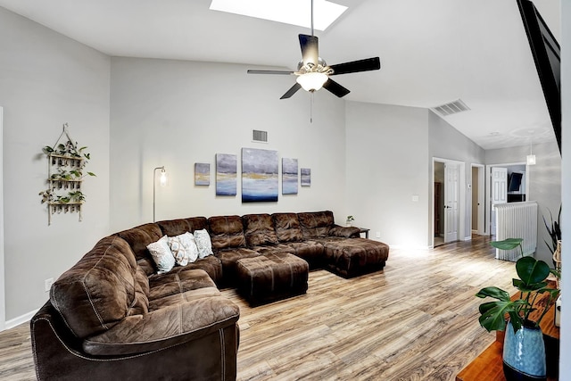 living room featuring wood-type flooring, lofted ceiling with skylight, and ceiling fan