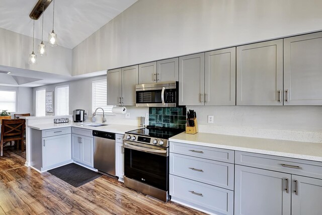 kitchen featuring decorative light fixtures, stainless steel appliances, sink, and gray cabinetry