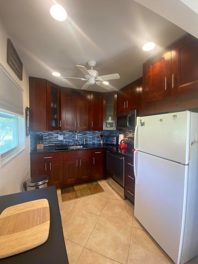 kitchen with light tile patterned flooring, sink, backsplash, appliances with stainless steel finishes, and ceiling fan