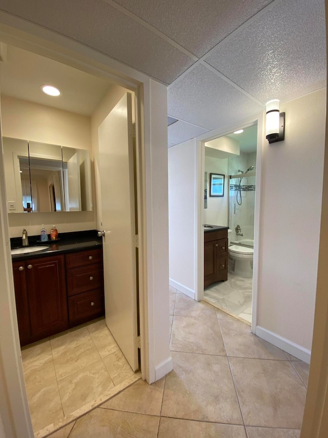 bathroom with tile patterned flooring, walk in shower, vanity, and toilet