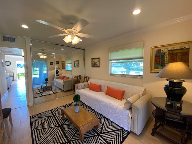 living room featuring ceiling fan, light wood-type flooring, crown molding, and a healthy amount of sunlight