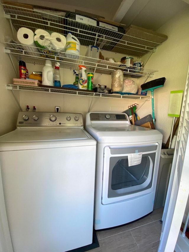 clothes washing area with washing machine and clothes dryer and tile patterned floors